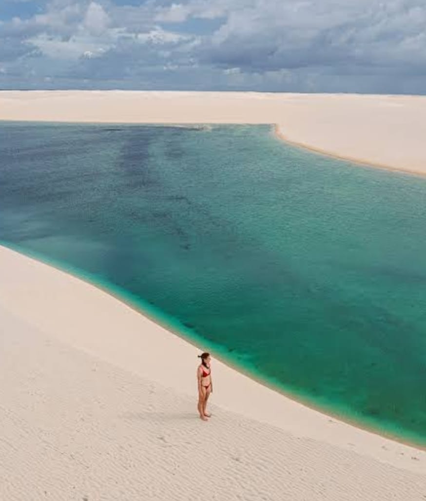 Viajante diante de lagoa cristalina entre as dunas